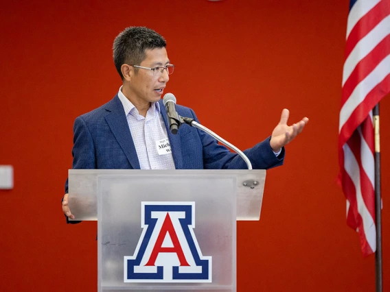 Michael Wu makes a speech at a podium with the University of Arizona logo.