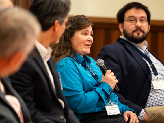 Three fellow panelists listen to Dawn Wellman, speaking with a microphone.