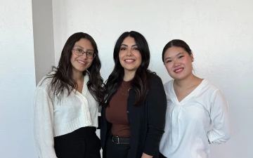 Three women with brown hair smile at the camera.