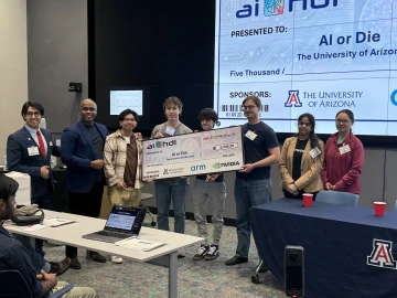 A group of students pose for a photo with a big check that reads $5,000.